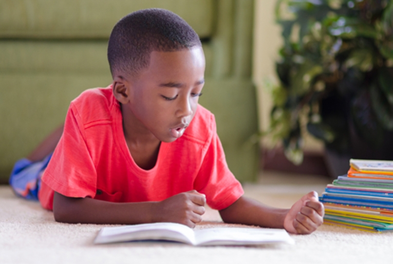 Young boy reading books on the floor