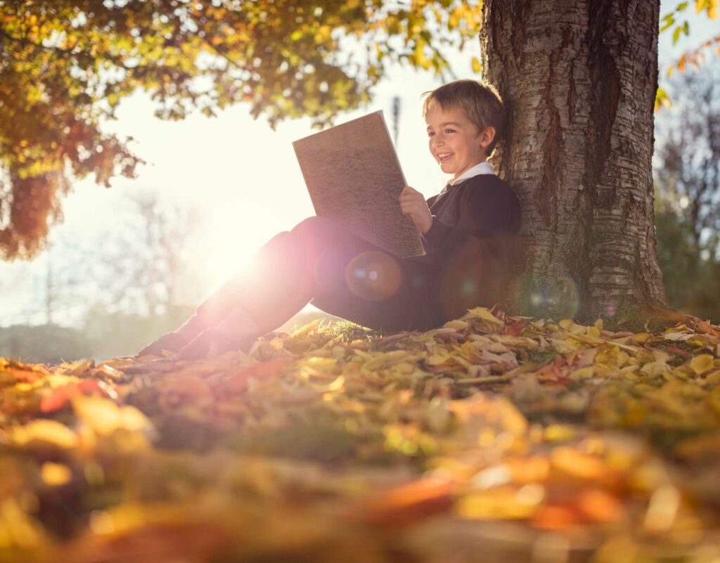 Boy reading outside under a tree